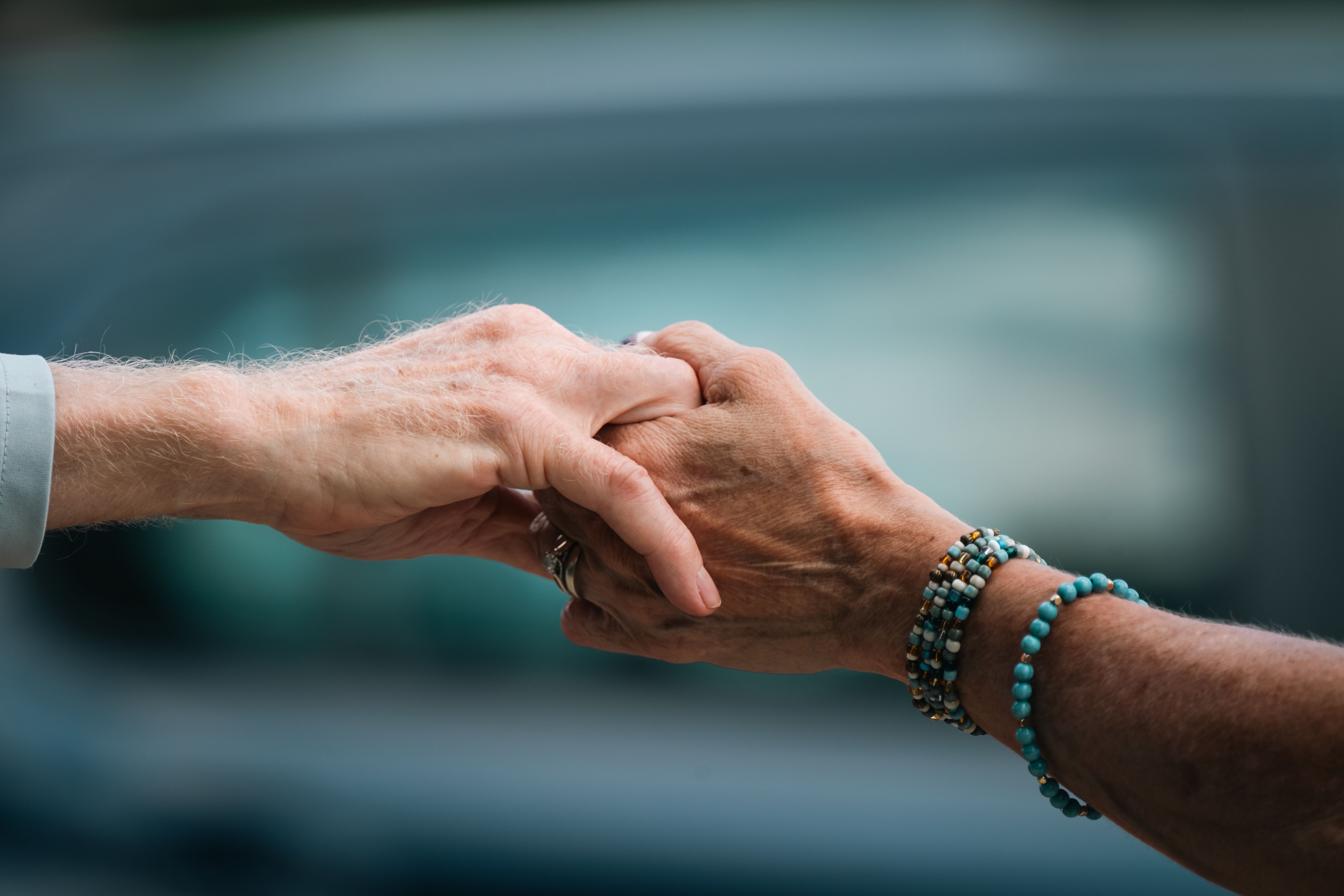A younger hand and an older hand clasped together.